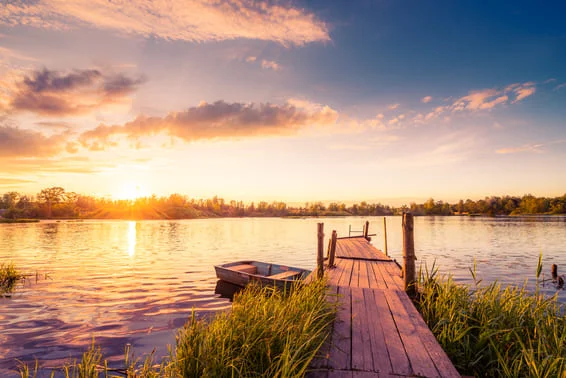 A small dock with a boat on a lake at sunset.